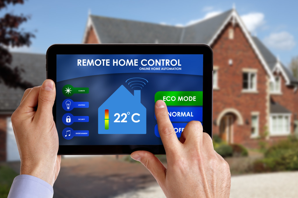 Holding a smart energy controller or remote home control online home automation system on a digital tablet. All screen graphics made up