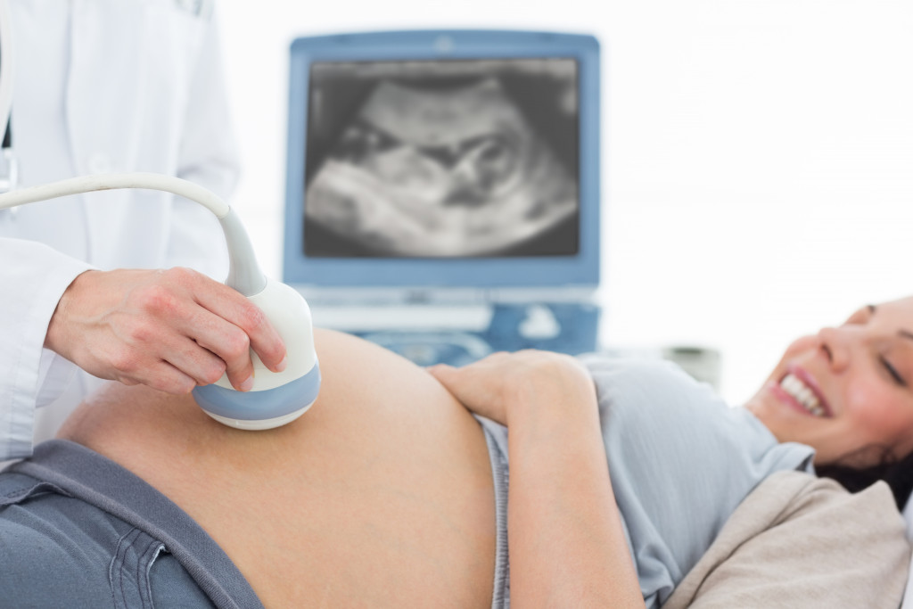 doctor performing ultrasound on pregnant woman in clinic