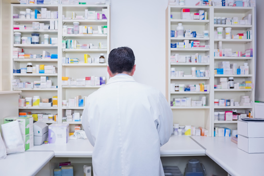 A pharmacist working in a lab coat in the pharmacy rear view
