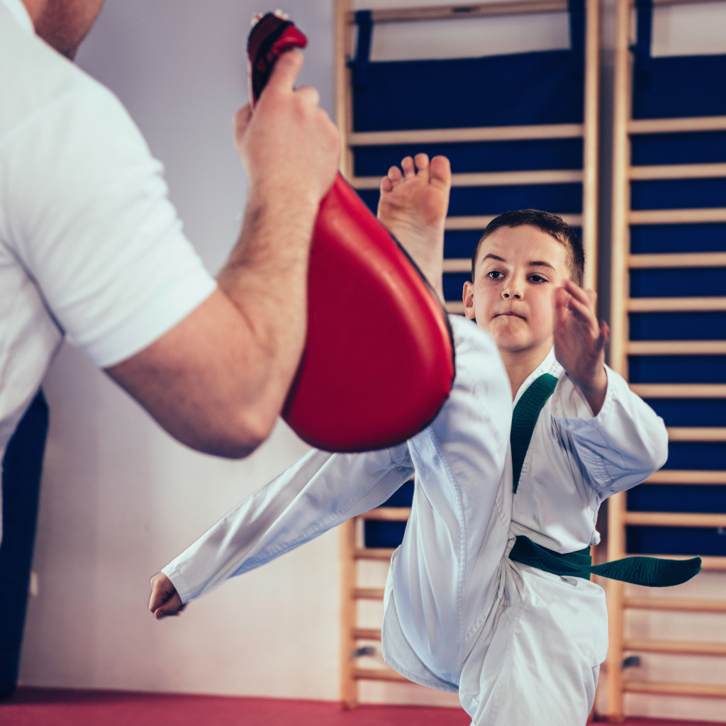 A kid practicing a front kick in Taekwondoin