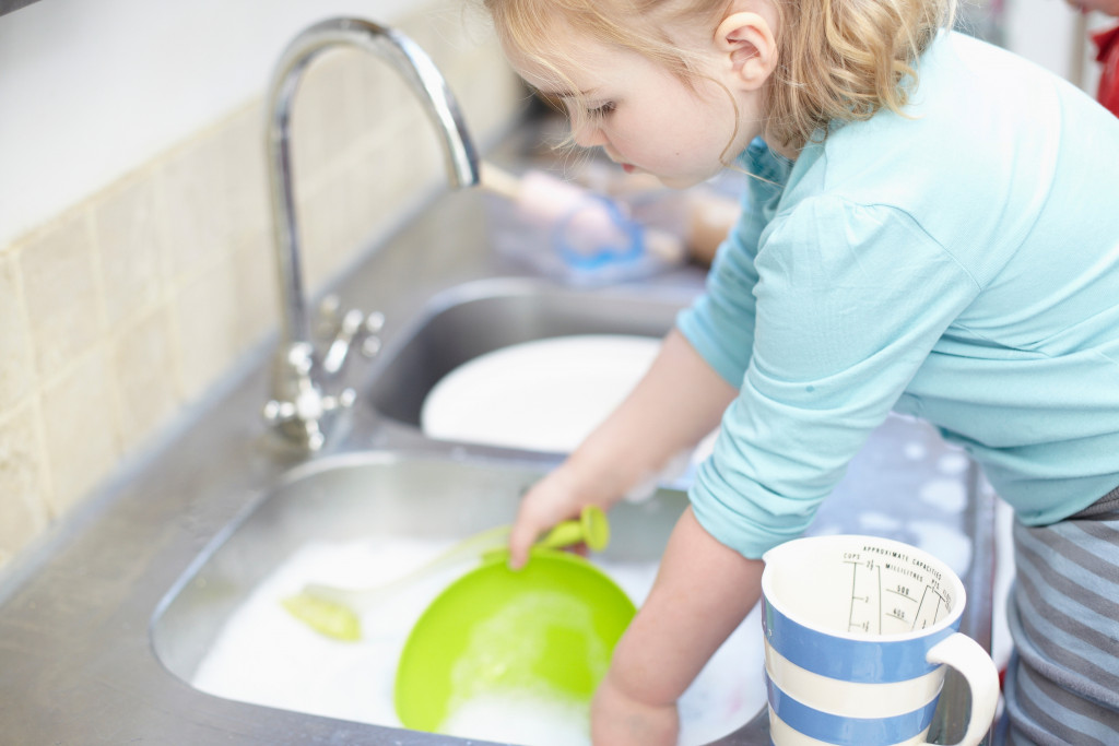 a little girl washing dishes