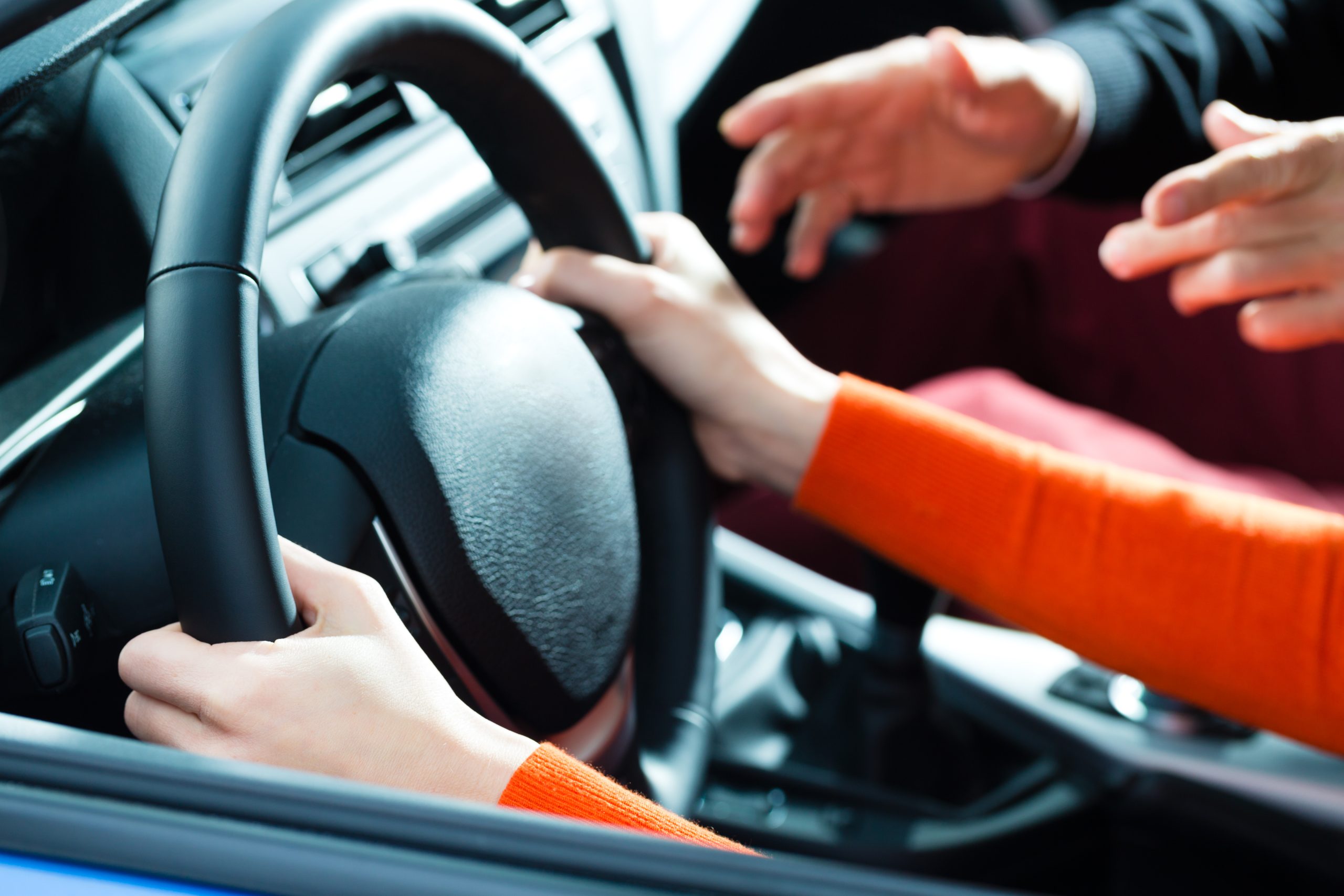 A driving instructor assisting a driver from the passenger seat