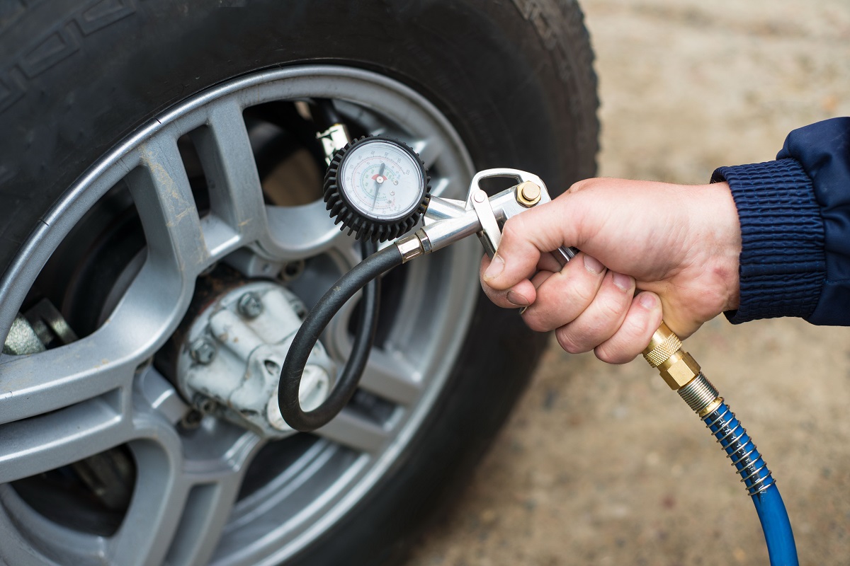 A person checking the tire pressure of a car