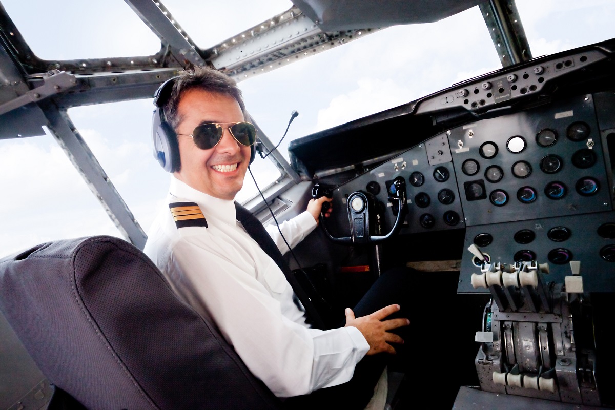 A pilot smiling to the camera while in a plane cockpit